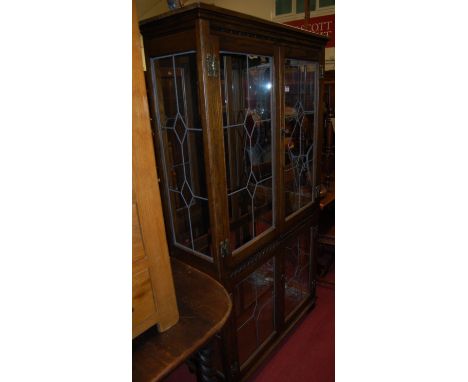 A contemporary Old Charm moulded oak and lead glazed four door display cabinet, having mirrored interior (one side panel dama