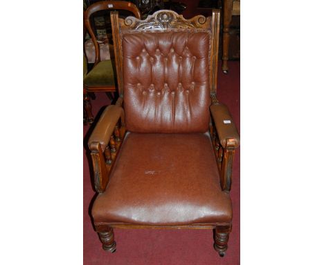 An Edwardian carved walnut and tan rexine button back upholstered open armchair raised on ring turned forelegs