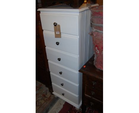 A white painted pine narrow chest of six long drawers, on bun supports, w.45.5cm; together with a painted wall shelf (2) 