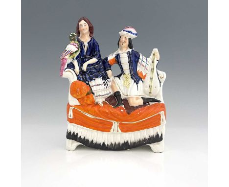 A Staffordshire figure of a seated man and woman on a chaise, circa 1870, female figure is modelled holding an exotic bird, t