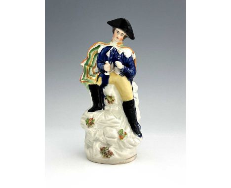 A Staffordshire portrait figure of Napoleon, circa 1840, modelled in military uniform and bicorn hat, stood on a naturalistic
