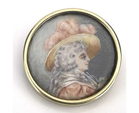 An antique circular portrait brooch, 18th Century lady in profile wearing a hat with pink feathers, on ivory, in a yellow met