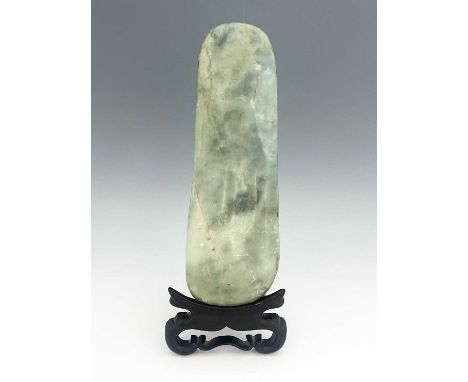 A Chinese polished jade boulder slab, neolithic axe head form, 39.5cm long, on a carved hardwood stand