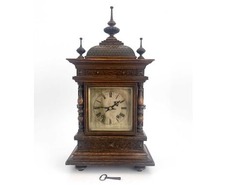 A Black Forest oak bracket clock, late 19th Century, of Germanic architectural form with finials, domed tiled roof, square si