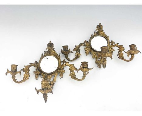 A pair of gilt metal girandoles, late 19th Century, of Rococo design, circular looking glasses, triple light branches, 30cm h
