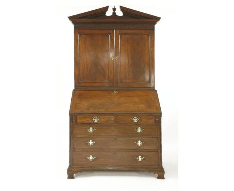 A George III mahogany bureau bookcase,the broken arched pediment centred with an urn, the plain panelled cupboard opening to 