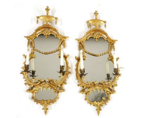 A pair of Chippendale period carved giltwood girandoles,each surmounted by a flaming Adam-style urn over a cartouche-shaped m