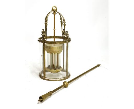 A large George III-style lacquered brass cylindrical hall lantern,with four foliate finials, a curved glass shade and lacquer