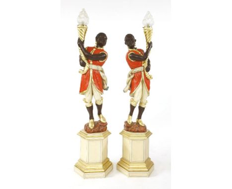 A pair of Venetian painted blackamoors,20th century, each figure holding a gilt cornucopia, wearing a red coat and beige bree