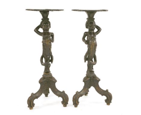 A pair of carved wooden and ebonised torchères, 19th century, each with a shaped top on a figural carved support, standing on