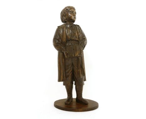 A carved oak figure of a boy,19th century, possibly depicting a 'Blue Coat', the boy wearing a long coat and holding a book, 
