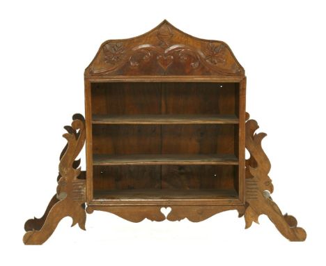 A French walnut shelf,early 20th century, the relief carved pediment decorated with leaves and hearts, over three shelves wit