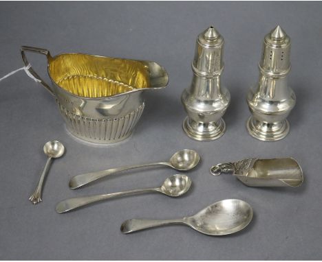 A silver cream jug, two silver pepperettes, three silver condiment spoons and two caddy spoons.