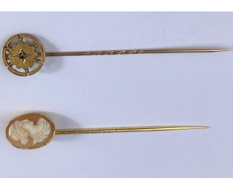 A cameo female head stick pin and another with circular flowerhead design set with diamond chip, both test as 9 ct, gross wei