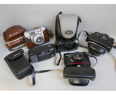 A collection of six cameras including Olympus, Ricoh in Lowpro case, two C35 Konica in cases, Yashica GSN body with broken le