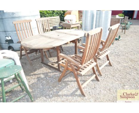 A teak garden table and four folding armchairs
