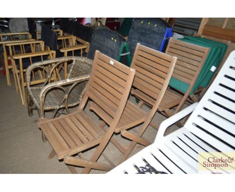 A set of four folding teak garden chairs with three cushions
