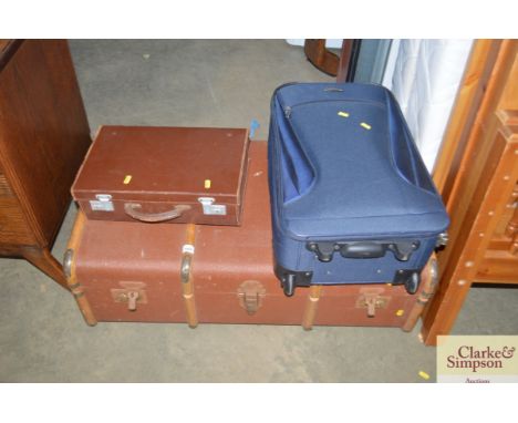 A wooden bound travelling trunk together with a suitcase and a small suitcase