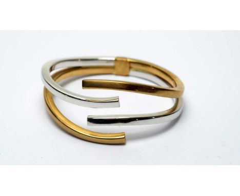 A 9ct yellow and white gold bangle, of open design with hinged back, 24.8g gross. 