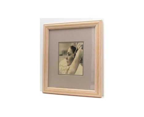 Elizabeth Taylor (1932-2011): a signed black and white photograph, portrait putting on a headdress, signed and inscribed 'Bes