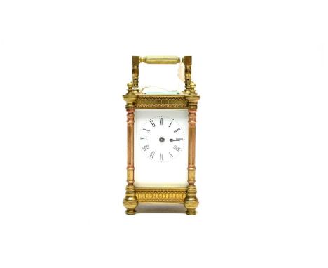 A late 19th Century brass carriage clock, the white dial with Roman numerals in black, with coppered fluted column supports, 