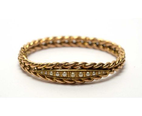A late Victorian 14ct yellow gold and graduated half pearl bangle, with plaited design, 14.8g gross. 
