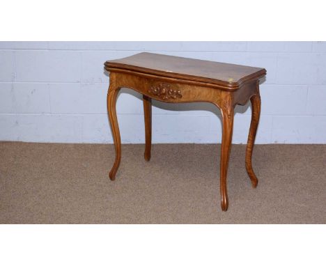 A late 19th Century figured walnut and serpentine fronted card table, the hinged folding top opening to reveal a baize lined 