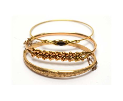 A 14ct yellow gold bangle, with plaited design, 9.1g; a 9ct yellow gold bangle, with floral engraving, 5.2g; and another bang