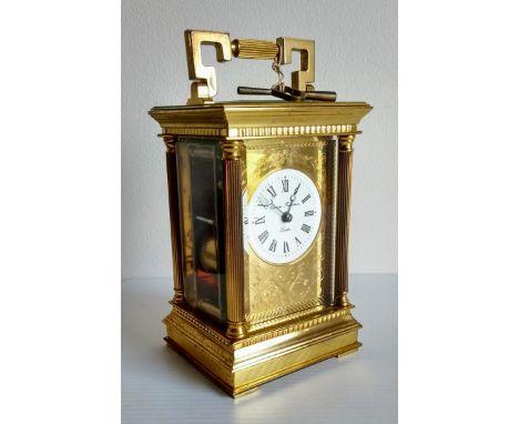 A brass carriage clock by Charles Frodsham, London, circular white dial with Roman numerals with a gilt floral mask, five gla