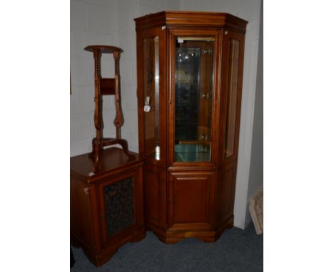 A reproduction cherrywood free-standing corner cupboard, with bevelled glass panels enclosing glass shelves, the base with a 