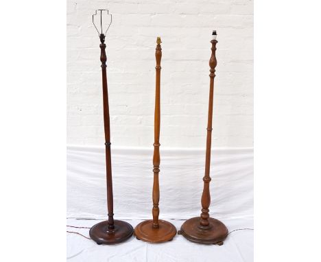THREE VINTAGE WOODEN FLOOR LAMPSall with turned columns and raised on circular bases with feet