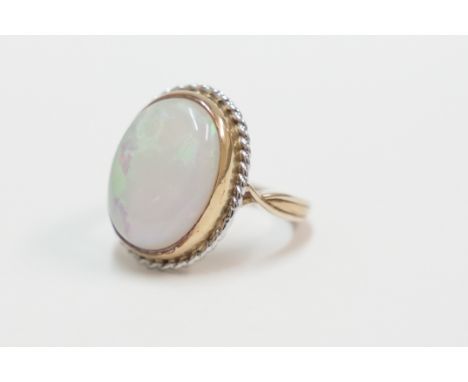 18ct yellow and white gold dress ring, set with one fine colour oval Opal, approx. 17mm x 12mm, approx. 9.5cts. Size M. Total