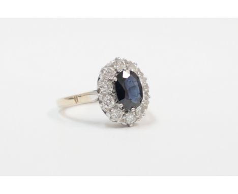 18ct yellow and white gold ring, set with centre oval Sapphire, surrounded by 10 round cut Diamonds. Size L. Total item weigh