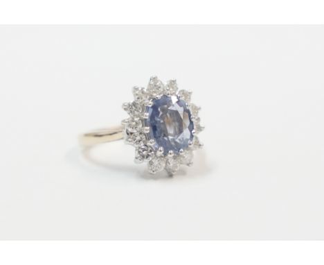 18ct yellow and white gold ring, set with cornflower blue Sapphire, surrounded by 14 round cut Diamonds. Size L. Total item w