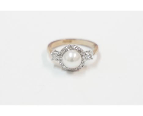 18ct yellow gold ring, set with single pearl, surrounded by 16 small Diamonds, and single Diamond in each shoulder. Size L. T