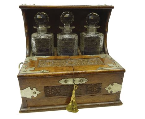 Edwardian oak three bottle tantalus with silver-plated mounts, carved floral panels, twin lidded front enclosing a four secti
