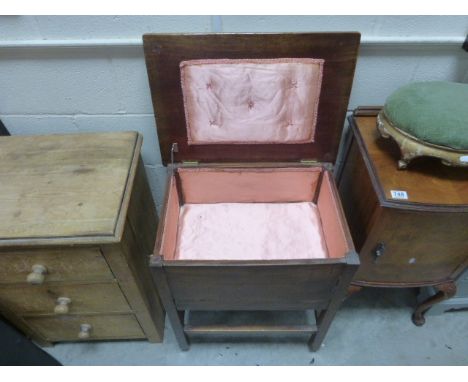 A vintage oak sewing cabinet with lifting lid raised on square legs and castors. .