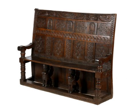 A 17th century and later oak bench settle. The panelled back carved with geometric patterns and the date '1662, TR', scroll a
