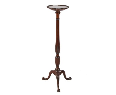 A Victorian mahogany jardiniere stand. The shaped top having a moulded edge, mounted on a turned and ribbed column and tripod