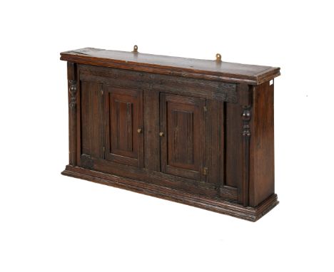 A 19th century oak wall hanging cupboard. The moulded pediment positioned over a pair of panelled doors having ribbed details