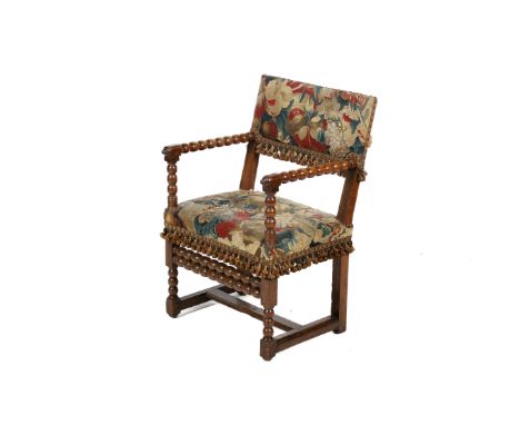 An 18th century walnut bobbin turned armchair. Having tapestry pad back and seat flanked by bobbin turned arms above the conf