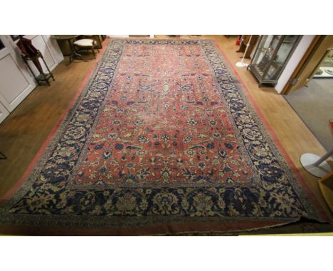 A large pink ground rug. With blue decoration and border of flowers and scrolling leaves. 580cm x 375cm.  Condition Report: T