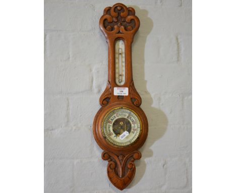 Edwardian carved oak aneroid barometer, thermometer gauge, 65cm; and another carved oak aneroid barometer, 49cm. (2)
