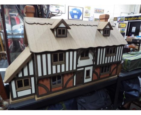 A dolls house in the style of a period country cottage with thatched roof with ten rooms and fully furnished to a high standa