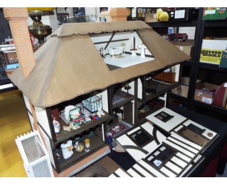 A dolls house in the style of a period country cottage with thatched roof with seven rooms and fully furnished to a high stan