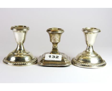 A hallmarked silver candle stick and a pair of sterling silver candle sticks, H. 8.5cm.