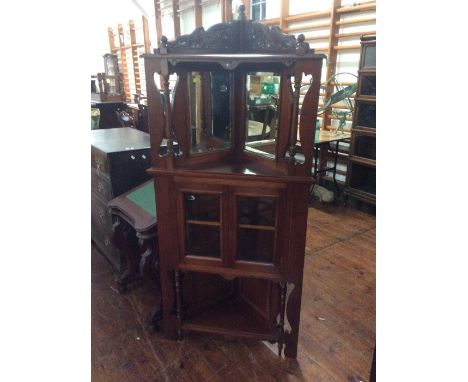 A reproduction walnut mirrored back corner cupboard, carved gallery top, above a mirror back on cabinet on turned supports, a