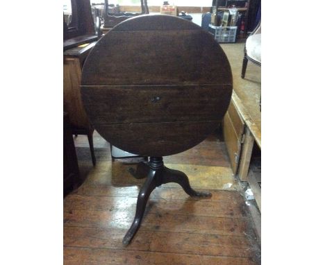 A George III oak tilt top table, circa 1780, turned barrel column on tripod cabriole supports padded feet.