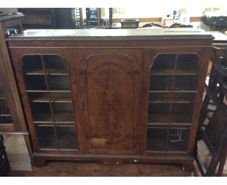 An early 20th century burr walnut veneered glazed bookcase cabinet, moulded cornice, two glazed doors with a panel door in th
