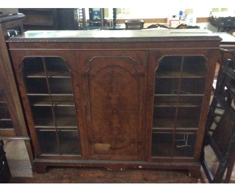 An early 20th century burr walnut veneered glazed bookcase cabinet, moulded cornice, two glazed doors with a panel door in th